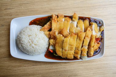 Çin restoranındaki ahşap bir masada, sebzeli, pirinçli ve soslu kızarmış tavuk dilimleri. Yukarıdan bakıldığında üst düzey, seçilmiş odak noktası, dar alan derinliği. 