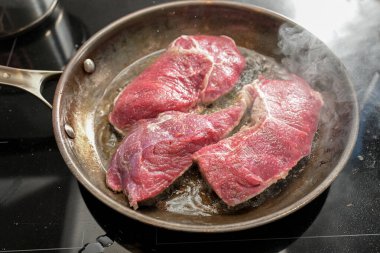 Taze çiğ biftekler kızgın yağda kızartılır. Karbon çeliğinden yapılmış tavada bol miktarda buhar bulunur. Et pişirilir.
