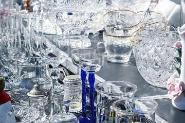 Çeşitli içki kadehleri, vazolar ve kaplarla bit pazarı tezgahı, bazıları parıldayan antika kristal camdan yapılmış, seçilmiş odak noktası, dar alan derinliği