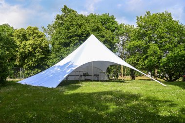 Beyaz tuvalden yapılmış büyük bir parti çadırı. Yaz festivali için parktaki bir çayırda değişken açılışlar, fotokopi alanı, seçilmiş odak noktası.