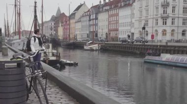 Kopenhag, Danimarka - 28 Ocak 2019: Kız turist Nyhavn Kanalı 'nda demirli yatlarla yürüyor (4K, 25fps)