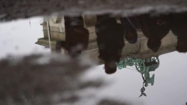 Brandenburg Kapısı Quadriga, yanında yürüyen insanların yansımaları olan bir su birikintisine yansıyor (4K, 30fps)