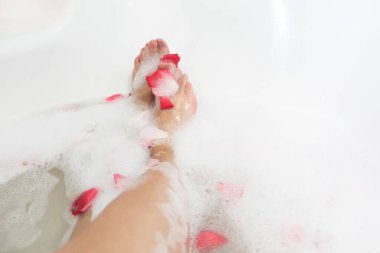 Relax. Romantic. Red rose petals in bath with legs girl. Valentine's Day