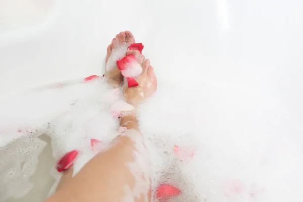 Relax. Romantic. Red rose petals in bath with legs girl. Valentine\'s Day