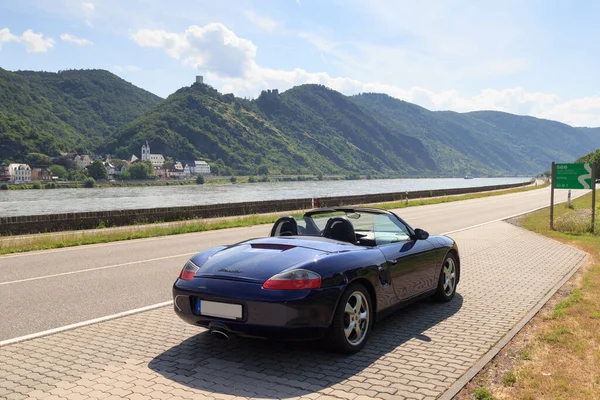Boppard, Almanya - 26 Haziran 2021: Mavi Roadster Porsche Boxster 986 Rhine geçidi ve kale panoraması. Araba, Alman otomobil şirketi Porsche tarafından üretilen iki koltuklu bir spor arabadır..