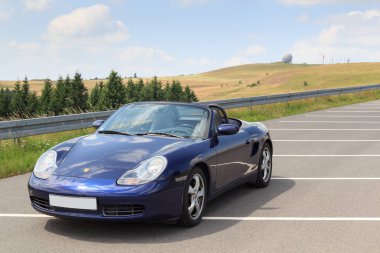 Gersfeld, Almanya - 23 Temmuz 2021: Mavi Roadster Porsche Boxster 986, Wasserkuppe Panorama ve Radar Kubbesi Rhoen Dağları 'nda. Araba, Porsche tarafından üretilen iki koltuklu orta-motorlu bir spor araba..