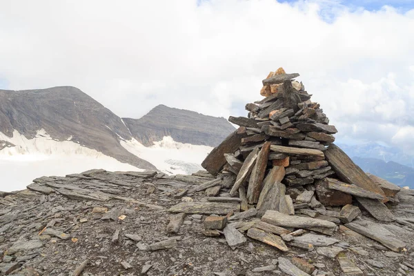 Cairn on summit of Eiswandbichl and mountain snow and glacier panorama with summit Grosser Baerenkopf and Hohe Dock in Glockner Group, Austria
