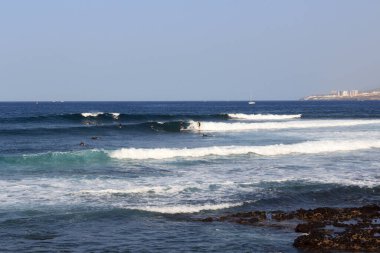 Sörf tahtası ve Atlantik Okyanusu manzarası üzerinde sörf yapan sörfçüler tatil beldesi Playa de las Americas, Kanarya Adası Tenerife, İspanya