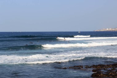 Sörf tahtası ve Atlantik Okyanusu manzarası üzerinde sörf yapan sörfçüler tatil beldesi Playa de las Americas, Kanarya Adası Tenerife, İspanya