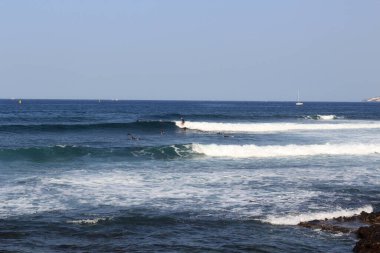 Sörf tahtası ve Atlantik Okyanusu manzarası üzerinde sörf yapan sörfçüler tatil beldesi Playa de las Americas, Kanarya Adası Tenerife, İspanya