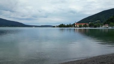 Almanya 'nın Bavyera kentindeki marina, kilise ve dağ manzarasıyla Tegernsee Gölü' ne doğru yaklaş.