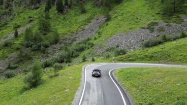 Santa Maria, İsviçre - 30 Temmuz 2023: Mavi Porsche 911 üstü açılır arabası Umbrail Geçidi 'ndeki yılan yollarında dağ alplerine doğru gidiyor. Araba Porsche tarafından üretilen bir spor arabadır..