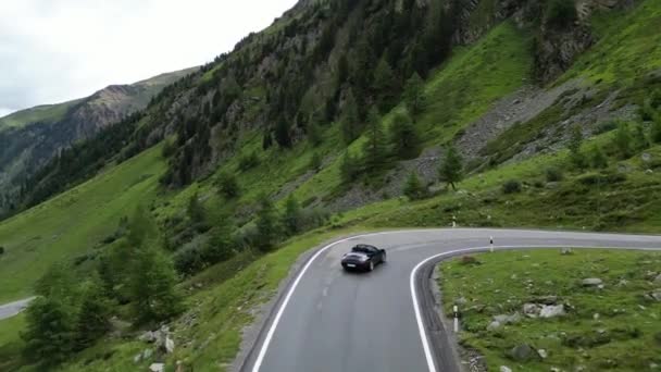 2023年7月30日 瑞士圣玛丽亚 蓝色保时捷911敞篷车在乌姆布拉伊尔山口的蛇形路上驶向高山阿尔卑斯山全景 这辆车是保时捷生产的跑车 — 图库视频影像