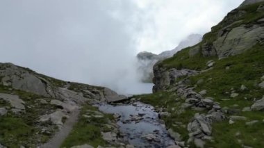 Güney Tyrol, İtalya 'daki Texel grubunda Spronser Gölü Langsee ve Grnsee (Yeşil Göl)' ün bulutları ve sisli panoramasına doğru dağ deresinin üzerinden uçmak
