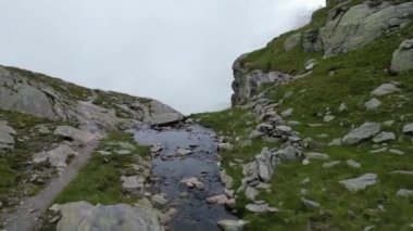 Güney Tyrol, İtalya 'daki Texel grubunda Spronser Gölü Langsee ve Gruensee (Yeşil Göl)' ün bulutları ve sisli panoramasına doğru dağ deresinin üzerinden uçmak