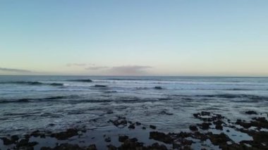 Güneş doğarken dalgaların yükseldiği Atlantik Okyanusu 'na doğru Kanarya Adası Tenerife, İspanya' daki Playa de las Americas tatil beldesinde uçuş.