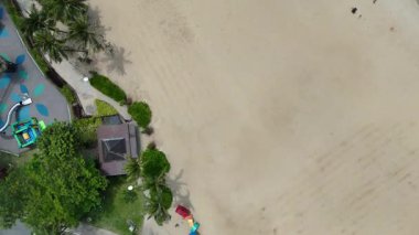 Singapur 'un Sentosa Adası' ndaki Palmiye ağaçlarıyla Siloso plajını tepeden aşağı gören uçuş.