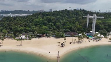 Sentosa Adası 'nda palmiye ağaçları ve barları olan Siloso sahili boyunca uçun ve arka planda Singapur' un silueti olsun.