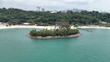 Sentosa Adası 'nda palmiye ağaçları ve barları olan Siloso sahili boyunca uçun ve arka planda Singapur' un silueti olsun.