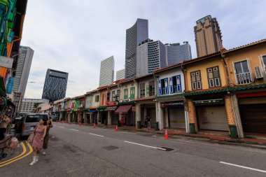 Singapur - 5 Ekim 2024: Kampong Glam ilçesinde gökdelenleri olan Arap Caddesi 'nde korunmuş dükkanlar ve palmiye ağaçları