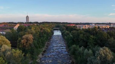 Günbatımında ağaçlarla Wertach nehri boyunca Panorama uçuşu ve Augsburg, Almanya 'da arka planda otel kulesi