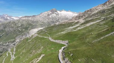 Furka Geçidi 'ndeki dağlık yoldan İsviçre Alpleri' ndeki Grstenhrner Dağı 'na doğru uçuyor.