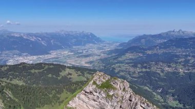 İsviçre 'nin İsviçre Alplerinde Pointe de Savolaires ve dağları, Rhone Vadisi ve Cenevre Gölü' nün zirvesinde oturan erkek yürüyüşçü (insan) etrafında yörünge uçuşları