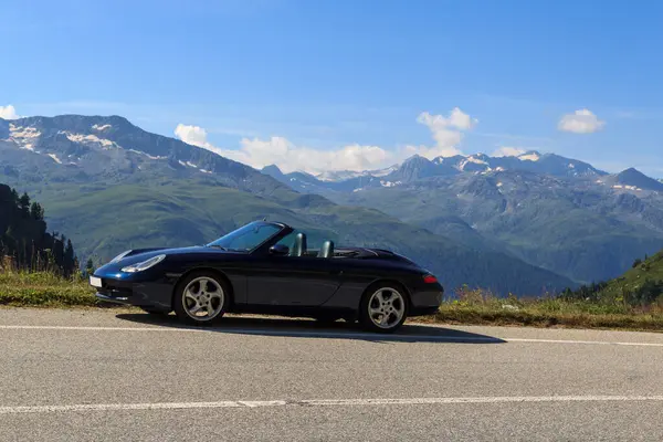 Oberwald, İsviçre - 11 Ağustos 2024: Mavi Porsche 911 üstü açık ve dağlı panorama İsviçre Alpleri 'ndeki Grimsel Pass yolunda.