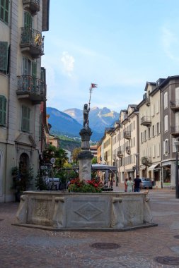 Sion, İsviçre - 11 Ağustos 2024: Eski Sion kasabasında arka planda dağ manzarası olan yaya bölgesi, dükkan ve çeşme. Sion, İsviçre 'nin Valais kantonunun merkezi kent..