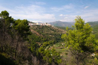 Ağaçların arasında Lucena del Cid köyü mavi gökyüzü ve bulutlarla çevrili bir günde Castellon, İspanya, Avrupa