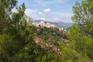 Ağaçların arasında Lucena del Cid köyü mavi gökyüzü ve bulutlarla çevrili bir günde Castellon, İspanya, Avrupa