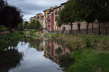 Ortaçağ Molina de Aragon köyünün şehir manzarası. Nehre bakan renkli evler ve bulutlu bir günde, İspanya 'nın Guadalajara kentinde tahta bir köprü.