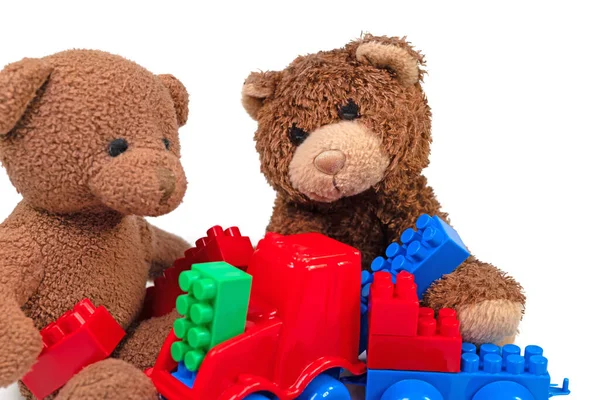 Plush bears and plastic building blocks against a white background