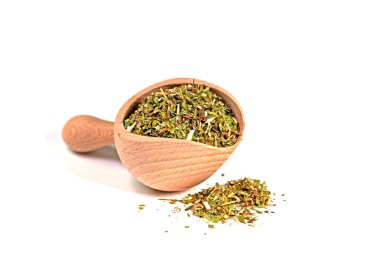 Beyaz arka planda bir baharat kepçesinde altın rengi çay