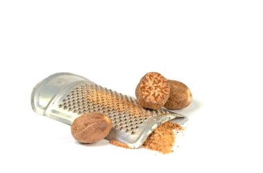 Nutmegs and grater against a white background clipart