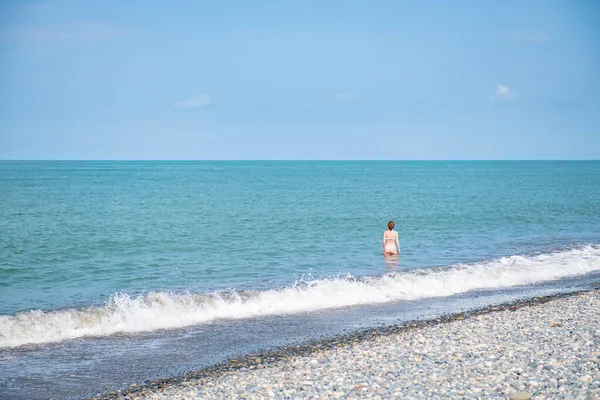 stock image one girl enters the sea in summer. High quality photo