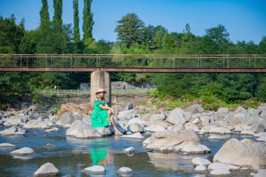 Şapkalı bir kız taşın üzerinde oturuyor. Yüksek kalite fotoğraf