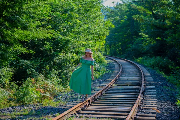 Stock image a girl in a green dress is walking on the railway. High quality photo