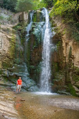 Pembe tişörtlü bir adam şelalede duruyor. Yüksek kalite fotoğraf