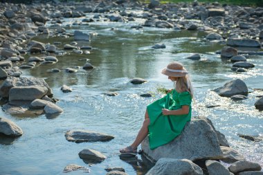 Şapkalı bir kız kayalıklarda oturuyor. Yüksek kalite fotoğraf