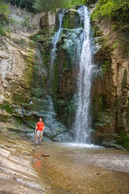 Pembe tişörtlü bir adam şelalede duruyor. Yüksek kalite fotoğraf