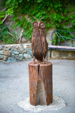 statue of an iron owl on a stump and a green wall. High quality photo