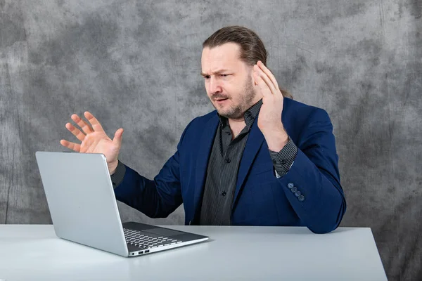 Angry man working on laptop in blue suit. High quality photo
