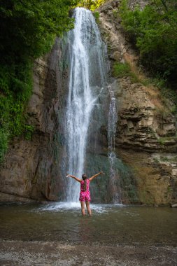 Ağaç ve Şelale 'nin ortasındaki kırmızı elbiseli kız. Yüksek kalite fotoğraf
