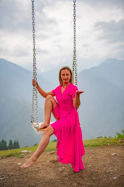 Dance with a swinging sun by a girl in a pink dress on a swing. High quality photo