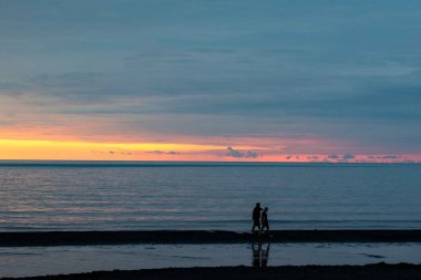 Kız ve erkek gün batımında Karadeniz kıyısında yürüyorlar. Yüksek kalite fotoğraf