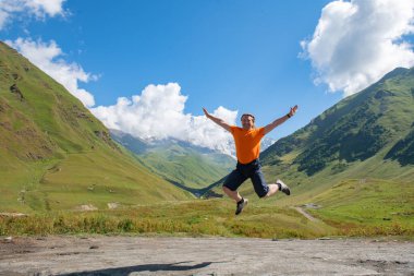 Bulut sörfçüsü: Yeşil Dağlara karşı turuncu bir tişörtle atlamak. Yüksek kalite fotoğraf