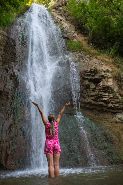 Cascading Dreams: Girl in Red Robes near the Waterfall. High quality photo