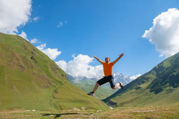 Bound for Freedom: A Man Jumps in his Orange T-Shirt, Embracing Nature. High quality photo