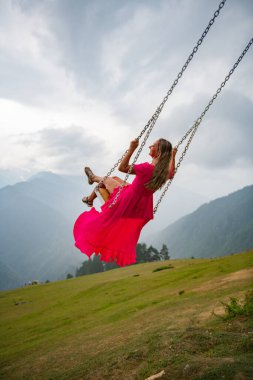 Hayatın salıncağında dönen pembe elbiseli bir kız. Yüksek kalite fotoğraf